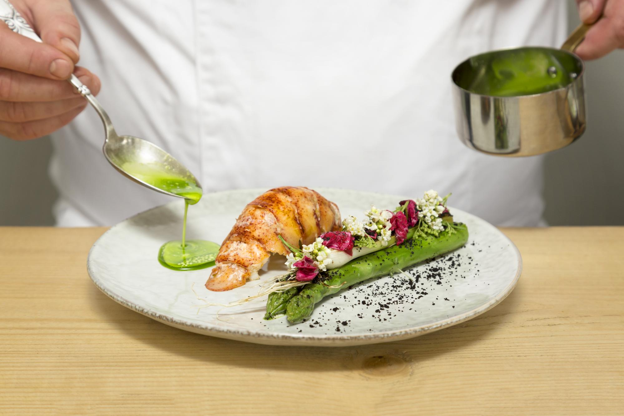 Chef placing finishing herbs on plated dish